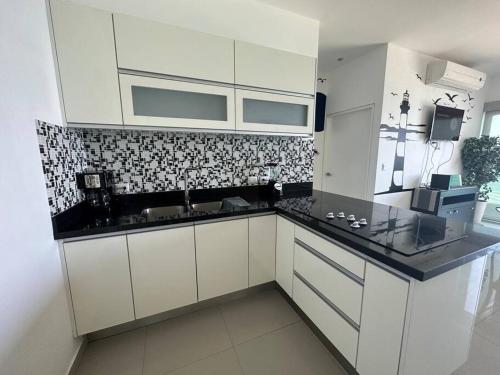 a kitchen with white cabinets and a black counter top at Torre EME 414 Vista al Mar in Mazatlán