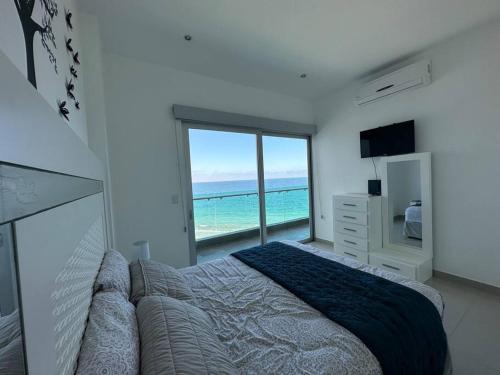 a bedroom with a bed and a view of the ocean at Torre EME 414 Vista al Mar in Mazatlán