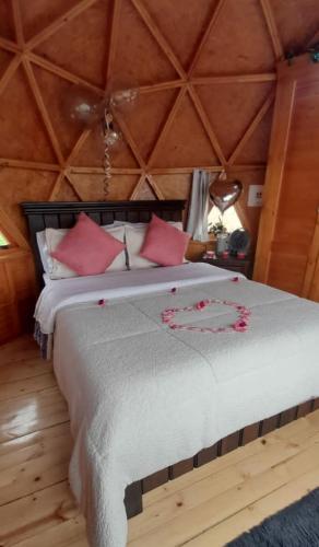 a bedroom with a large bed with red pillows at Glamping y Cabañas el Encanto- los novios in Tota