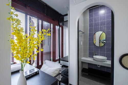 a bathroom with a table and a vase with yellow flowers at Nhà Bà Tư Boutique Homestay in Vung Tau