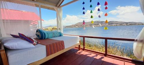a bed on a balcony with a view of the water at Uros Amaru Marka Lodge in Uros