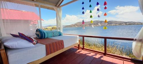 Bett auf einem Balkon mit Blick auf das Wasser in der Unterkunft Uros Amaru Marka Lodge in Uros