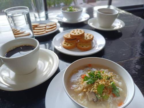 una mesa con platos de comida y tazas de café en Pruksa Siri View, en Saraburi