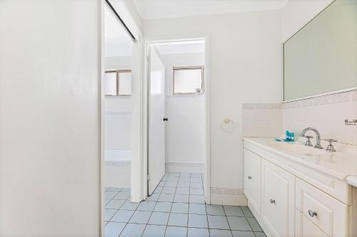 Baño blanco con lavabo y espejo en 28 Nioka Street, en Dalmeny