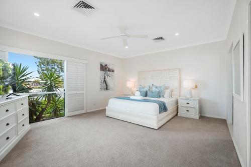 a white bedroom with a bed and a window at SEACLUSION 5 bed waterfront, sleeps 12 in Gold Coast