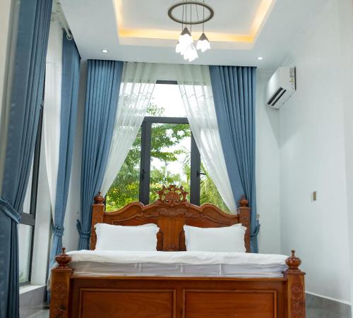 a bedroom with a bed with blue curtains and a window at Damnak Borey Resort in Kampot