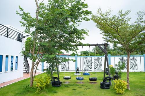 a garden with two trees and a swing set at Damnak Borey Resort in Kampot