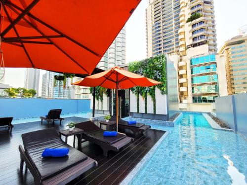 a pool with tables and umbrellas and a swimming pool at Citrus Sukhumvit 13 Nana Bangkok by Compass Hospitality - Newly Renovated in Bangkok
