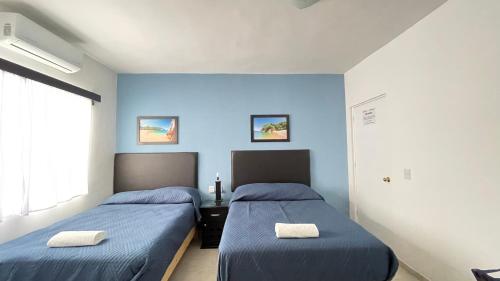 two beds in a room with blue walls at Habitacion Privada Ejecutiva Minisplit Amenidades 2 in Castillo Teresa