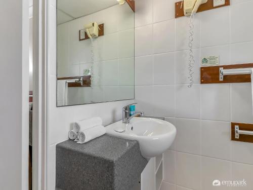 a white bathroom with a sink and a mirror at Studio 3 ENDEAVOUR INN in Emu Park
