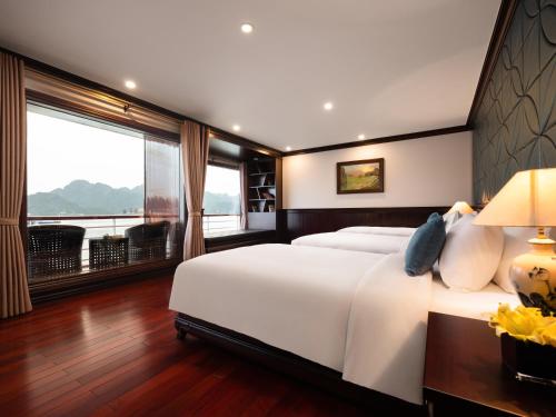 a bedroom with a large white bed and large windows at Aqua Of The Seas Cruise Halong in Ha Long