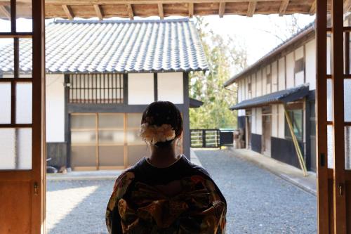 a man is looking out of a window at 佐渡島に残る築130年の伝統的な古民家｜東夢 in Sado