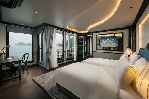 a bedroom with a large bed and a desk and windows at Lapinta Luxury Cruises in Ha Long