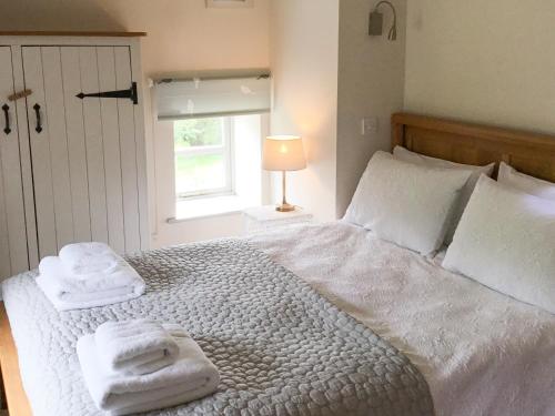 - une chambre avec un grand lit blanc et des serviettes dans l'établissement Crabapple Cottage, à Llanyblodwel