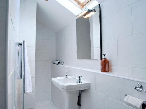 La salle de bains blanche est pourvue d'un lavabo et d'un miroir. dans l'établissement Crabapple Cottage, à Llanyblodwel
