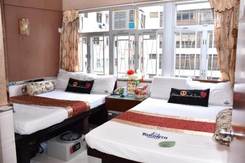 een kamer met 2 bedden en een raam bij London Guest House in Hong Kong