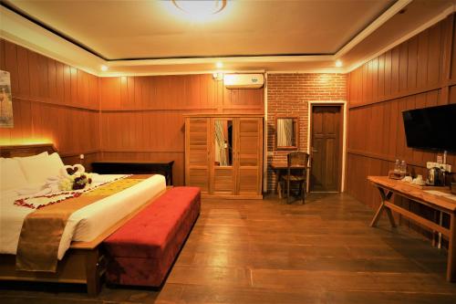 a bedroom with a bed and a desk and a television at Kasuari Exotic Resort Magelang in Magelang