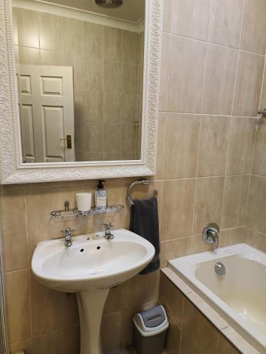 a bathroom with a sink and a mirror and a tub at LemonBlossom in Bloemfontein