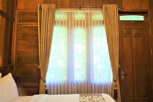 a bedroom with a bed and a window with curtains at Kasuari Exotic Resort Magelang in Magelang