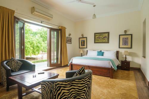 une chambre avec un lit, une table et des chaises dans l'établissement amã Stays & Trails Abhay Villa Bisalpur, Jodhpur, à Jodhpur
