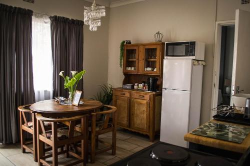uma cozinha com uma mesa e um frigorífico branco em LemonBlossom em Bloemfontein