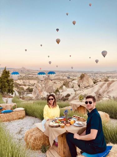 a man and woman sitting at a table with hot air balloons at Wish Cappadocia in Uchisar