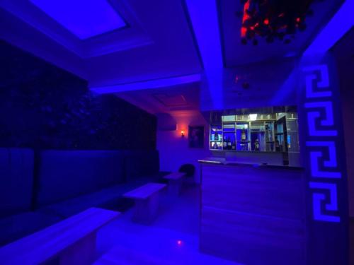 a room with blue lights and a bar with benches at Palazzo Apartments in Ikeja