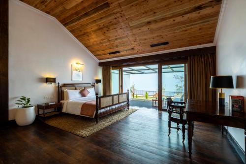 a bedroom with a bed with a wooden ceiling and a desk at ama Stays & Trails Puttabong Cottage, Darjeeling in Darjeeling