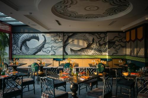 a restaurant with tables and chairs and a mural at SMARANA Hanoi HERITAGE in Hanoi