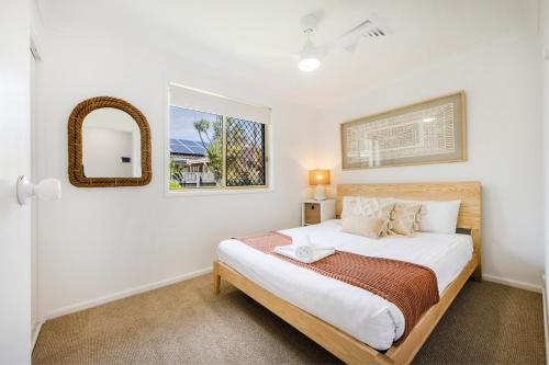 a bedroom with a bed and a mirror at Kailani Beach House - LJHooker Yamba in Yamba