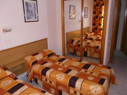 a hotel room with three beds and a mirror at Apartamentos Beni-Beach in Benidorm