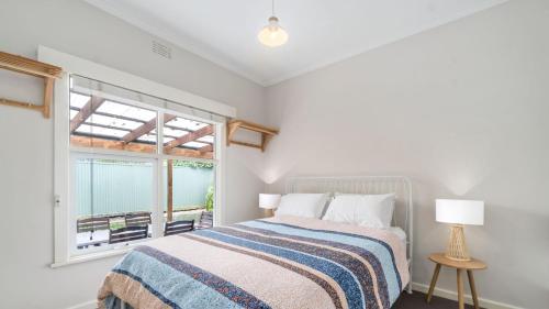 a white bedroom with a bed and a window at Nelson By The Bay in Apollo Bay