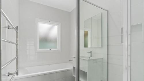a white bathroom with a shower and a sink at Nelson By The Bay in Apollo Bay