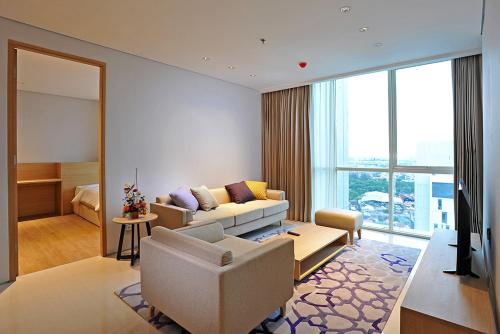 a living room with a couch and a room with a bed at Midtown Residence Surabaya in Surabaya