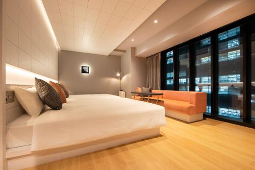 東京的住宿－karaksa hotel colors Tokyo Yaesu，卧室配有一张白色的大床和一张沙发。