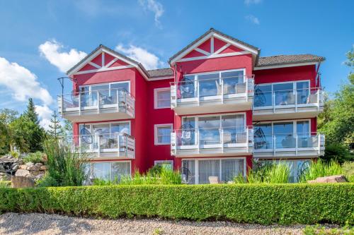 a red building with bushes in front of it at Maarberg Resort in Schalkenmehren