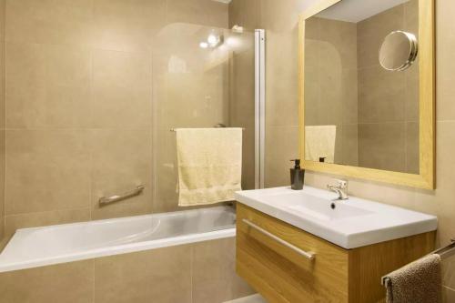 ein Badezimmer mit Waschbecken, Badewanne und Spiegel in der Unterkunft 1 Bed Apartment Sleeps 4 with Pool in Santo António