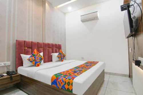 a bedroom with a large white bed with colorful pillows at FabHotel Yellow Leaf in Ludhiana