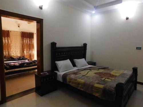 1 dormitorio con cama y espejo grande en Usmania Guest House, en Abbottābād
