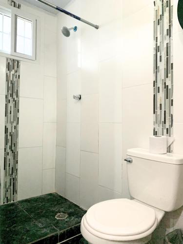a white bathroom with a toilet and a shower at Pacific Coast Hotel in Playa Bonita Village