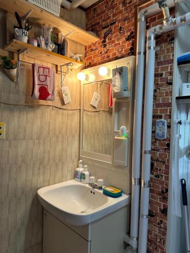 a bathroom with a sink and a brick wall at 民宿 渡辺 in Iwanai