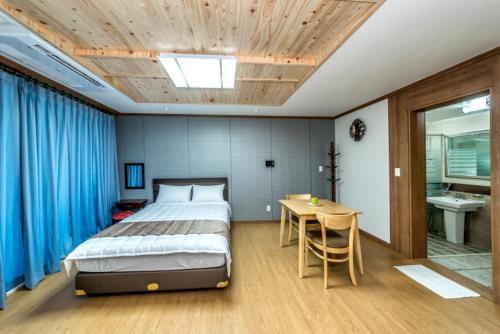 a bedroom with a bed and a table and blue curtains at Sea and Wave in Seogwipo