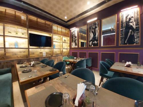 Hotel SS Grandeur في Alambagh: غرفة طعام مع طاولات وكراسي وتلفزيون