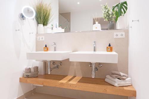 uma casa de banho com 2 lavatórios e toalhas numa prateleira de madeira em View 91 Strandliebe em Scharbeutz