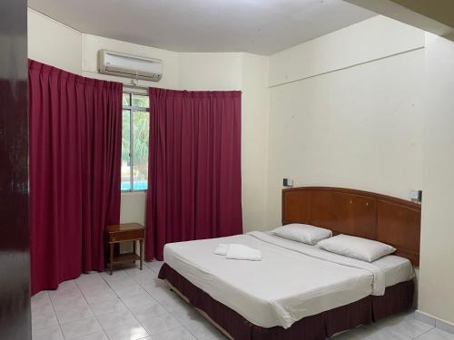 a bedroom with a large bed with red curtains at KUHARA COURT APARTMENT SUITE in Tawau