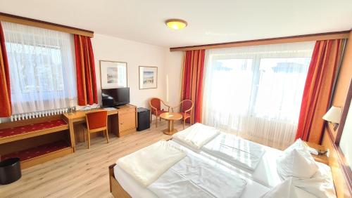 sala de estar con cama, escritorio y ventanas en Thermenhotel Tannenhof - Ihr Wohlfühl-Hotel en Bad Füssing