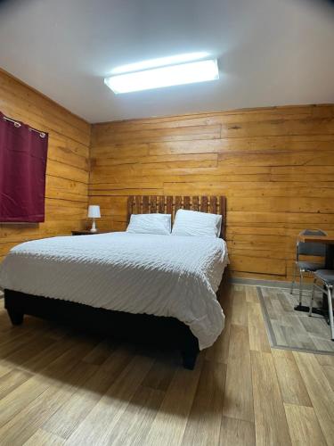 Soldotna Lodge في سولدوتنا: غرفة نوم بسرير كبير وبجدران خشبية