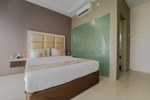 a bedroom with a large bed and a glass wall at Osaka Hotel Batam in Nagoya