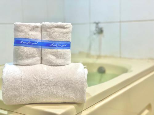 una pila de toallas blancas en un mostrador junto a la bañera en 山水妍溫泉會館-台東館, en Taimali