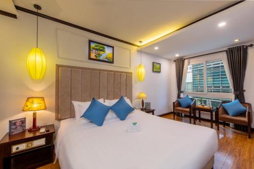 a bedroom with a large white bed with blue pillows at Babylon Grand Hotel & Spa in Hanoi